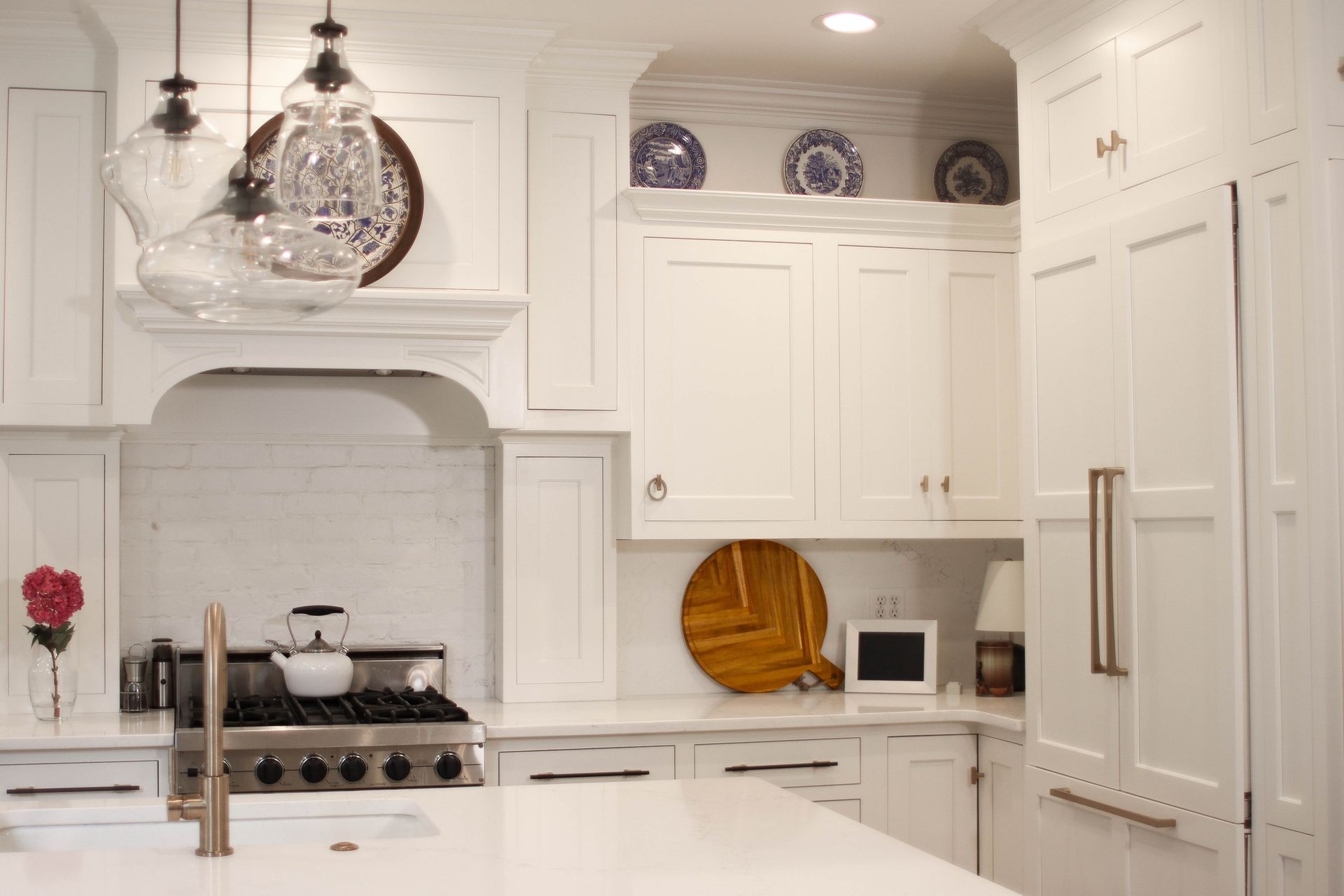 Modern kitchen with white cabinets, stainless steel stove, and hanging glass light fixtures.